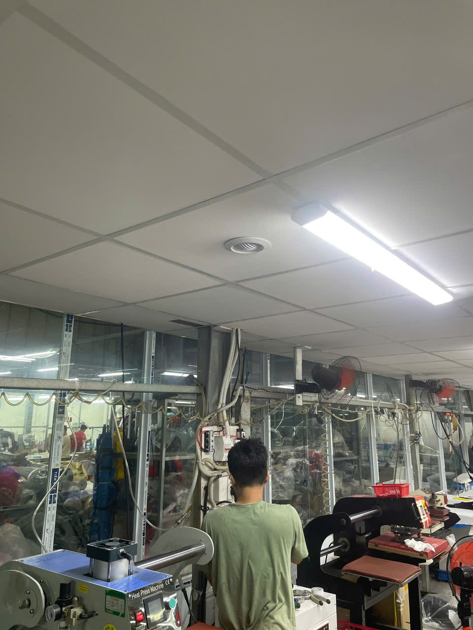 Kỹ thuật viên kiểm tra hệ thống ống gió trên trần xưởng may trước khi hoàn thiện